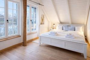 a white bed in a room with windows at Haus am See Kamin privater Seezugang in Warendorf