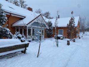 a house covered in snow with a bench in front of it at Kukšu muiža in Kukšas