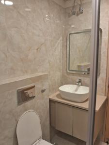 a bathroom with a sink and a toilet and a mirror at Hotel Immense Plaza in Jāmb