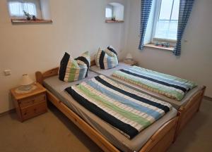 a bed with a wooden frame in a room with two windows at Ferienwohnanlage John Alter Stall in Burg
