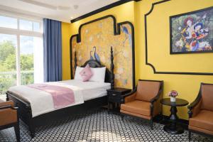 a bedroom with a large bed and two chairs at New Pearl Hotel HCM in Ho Chi Minh City
