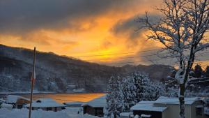 a winter sunset with snow covered trees and a building at Elan Villa Nojiri in Shinano