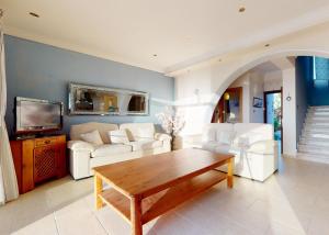 a living room with white furniture and a wooden table at Villa Magic Sunset in Kyrenia