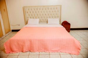 a bedroom with a bed with an orange blanket at Welcome Inn Guest house in Kigali