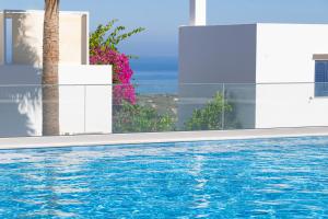 a swimming pool with a palm tree next to a building at Outstanding Apartment in an Unique Aegean Inspired Settlement in Agia Triada +58 photos