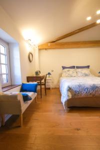 a bedroom with a bed and a chair and a table at Les Nuits du Pastelier in Teulat