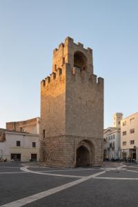 a tall brick tower with an archway in a street at ACQUARIO DEI FRALLE in Oristano