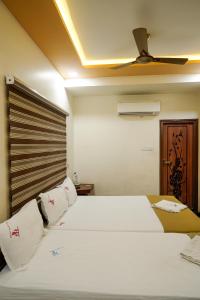 a bedroom with a bed with white sheets and a ceiling at Thai Residency - Opp to Bus Stand in Dhārāpuram +44 photos