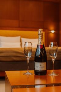 a bottle of wine and two glasses on a table at Garni Hotel Aleksandar in Novi Sad