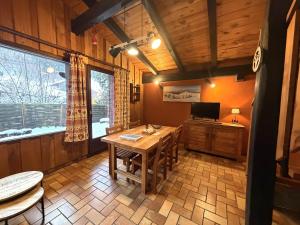 a dining room with a wooden table and a television at LA POMME DE PIN 1 Appartement avec terrasse in La Bresse