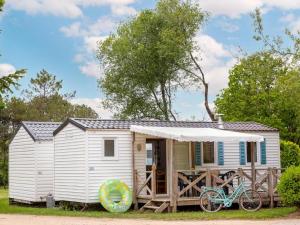 a white tiny house with a bike parked outside at Les mobilhomes du vélodrome in Albert