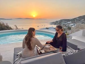 two women sitting at a table in front of a pool at Villa Vanita Agios Ioannis Mykonos in Agios Ioannis Mykonos +60 photos