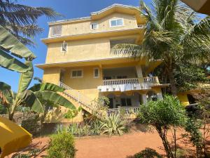 a large yellow building with palm trees in front of it at The Mamta Courtyard Anjuna in Anjuna
