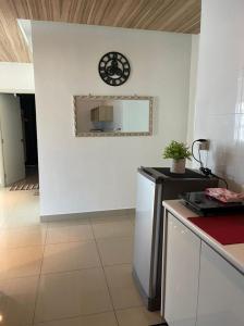 a kitchen with a white wall with a clock on the wall at Arte Plus Homestay Condo in Kuala Lumpur +5 photos