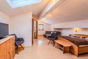 a bedroom with a bed and a tv and chairs at Appartements Kaltenbach in Kaltenbach