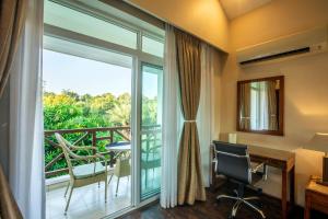a room with a desk and a large window with a balcony at Resort De Coracao - Corbett , Uttarakhand in Rāmnagar