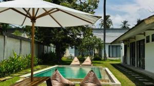 a pool with an umbrella and pillows next to a house at Sefirot Studios in Kuta Lombok