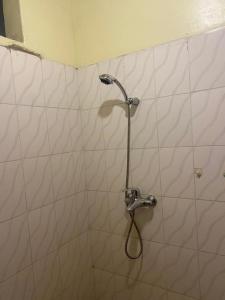 a shower with a hose in a white tiled bathroom at Welcome Inn Guest house in Kigali