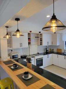 a kitchen with white cabinets and a wooden table at Olkeleo HummingBird Cottage in Naivasha
