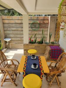 a patio with yellow chairs and a table with a cup on it at Olkeleo HummingBird Cottage in Naivasha +4 photos