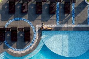 a woman laying on a bench next to a swimming pool at Samsara Hotel Pattaya in Pattaya South