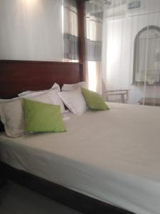 a bed with green and white pillows on it at Solace Transit Villa in Katunayaka