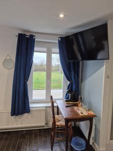 a room with a table and a window with blue curtains at O fil de l'eau in Tétaigne