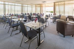 uma sala de jantar com mesas e cadeiras e pessoas a comer em Pressoir Hôtel em Saint-Calais