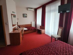 a hotel room with a bed and a desk and window at Motel Aleksandar in Pojate