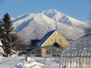 a house with a snow covered mountain in the background at Hillview cottage Sanfurano in Kami-furano