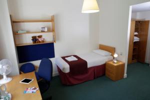a small room with a bed and a table and chairs at Beit Hall in London