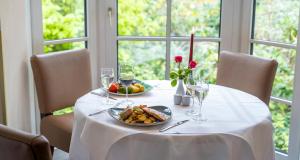 a table with a plate of food and wine glasses at PLAZA INN Schmöker-Hof in Norderstedt