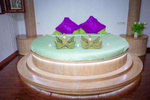 a large bed in a room with purple and green pillows at Olivier Boutique in Chiang Mai
