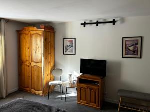 a living room with a television and a wooden cabinet at Devonshire Lodge Chalet in Bansko