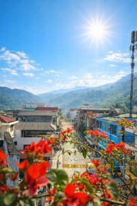 a view of a city with red flowers in the foreground at Thuỳ Dương Hotel Cao Bằng in Bảo Lạc