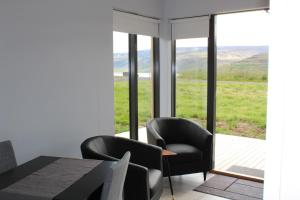 a dining room with a table and chairs and a large window at Systrakot - Studio Apartments in Talknafjordur