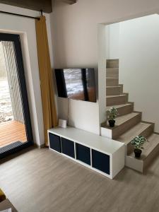 a living room with a tv on the wall and stairs at Apartmán Vališka in Horní Bečva