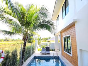 a swimming pool in front of a house with a palm tree at Vanesa Serenity Villa 1 in Ban Chong Phli