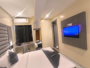 a room with a bed and a tv on a wall at Sahara Inn in Mumbai
