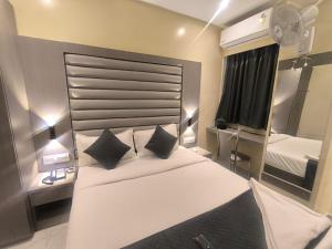 a bedroom with a large white bed with black pillows at Sahara Inn in Mumbai