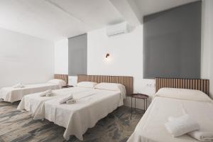 three beds in a room with white walls and wooden floors at Hotel Rural Macondo in Trujillanos +45 photos