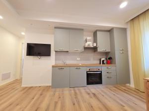 a kitchen with white cabinets and a flat screen tv at Lovely Corner 2 in Porto Santo Stefano