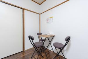 a table and four chairs in a room with a wall at Kasuga Good Place House in Kasugabaru