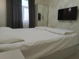 a bedroom with two beds and a flat screen tv on the wall at Bobur Guest House in Khiva