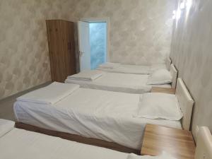 two beds in a small room with a window at Bobur Guest House in Khiva