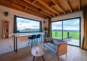 a living room with a couch and a desk and a large window at Le perchoir in Cuverville