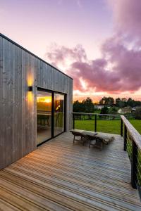 a wooden deck with a bench and a sunset at Le perchoir in Cuverville