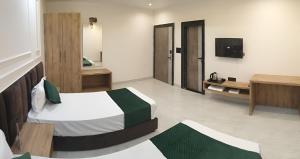 a hotel room with two beds and a television at Hotel The Coal in Alīgarh