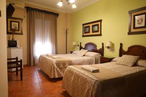 ein Hotelzimmer mit zwei Betten und einem Fernseher in der Unterkunft Hostal Rocio in Sanlúcar la Mayor