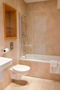 a bathroom with a toilet and a tub and a sink at Regent House deluxe 2 bedroom apartment in Harrogate